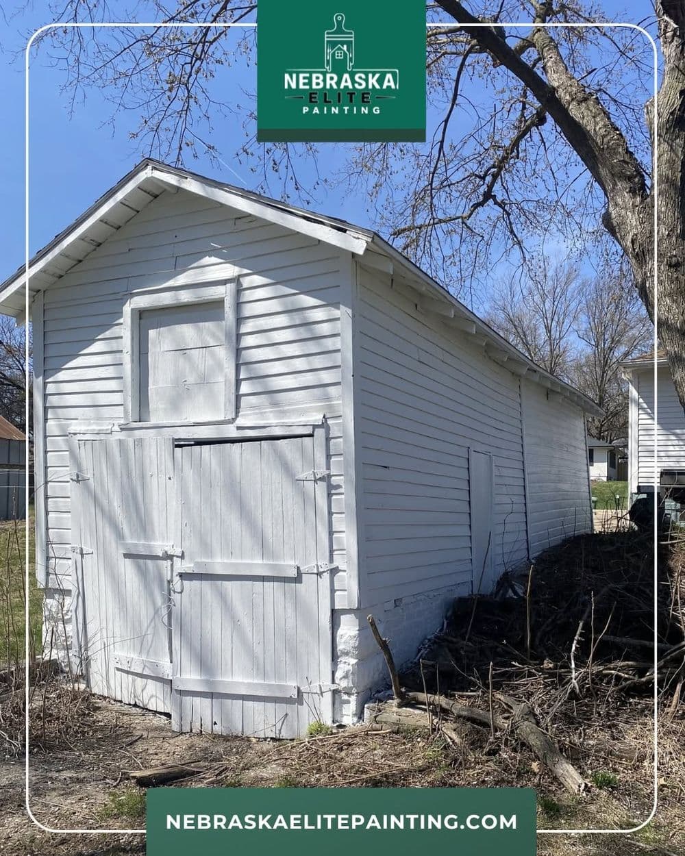 White wooden shed in a yard, showcasing Nebraska Elite Painting's work and craftsmanship.