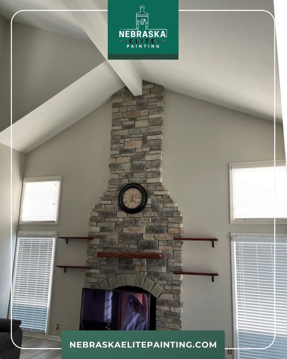 Modern stone fireplace with clock and wooden shelves in a bright living room by Nebraska Elite Painting.