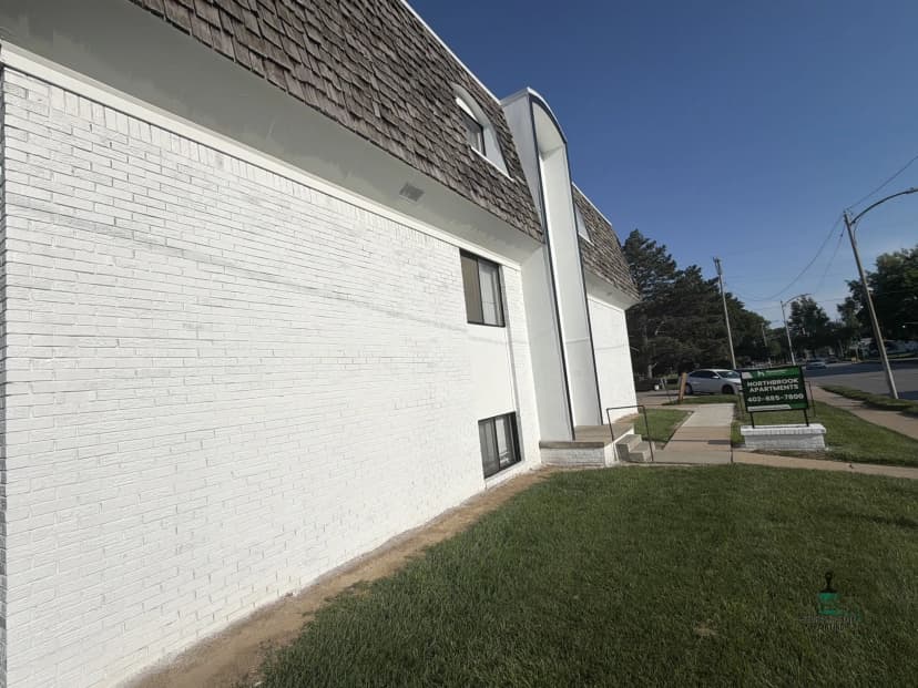 White building exterior with a textured roof and green signage on a sunny day.